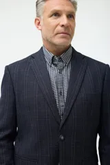 Blazer de corte clásico en color azul marino con patrón de cuadros sutiles. Presenta cierre frontal de un botón, solapas de muesca y bolsillos laterales con solapa.