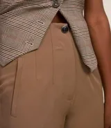 Pantalón zanahoria de sastrería color blanco, con cintura alta, trabillas y botón contrastante.