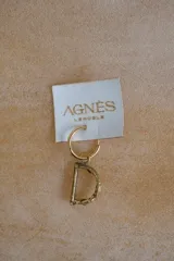 Arete de aro pequeño dorado con dije colgante de la letra "D" con acabado rústico y textura irregular.