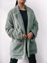 Saco verde de tela tipo teddy, con cuello solapa, corte oversize, mangas largas y bolsillos frontales.