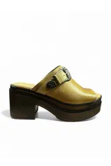 Zueco de punta abierta color tostado, con plataforma alta símil madera, taco ancho y una tira en el empeine decorada con hebilla y aplique metálico estilo western.