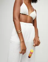 Pulsera rígida de aleación de metales bañada en oro de 18k, con diseño abierto de doble vuelta y logo de la marca grabado en uno de los extremos.