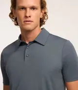 Camisa polo masculina de manga corta, confeccionada en tejido técnico de poliamida con elastano. Presenta cuello inglés con tapeta de tres botones, ofreciendo propiedades de secado rápido, elasticidad y confort térmico.