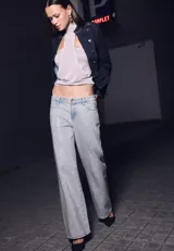 Jean de corte recto y tiro bajo, confeccionado en denim con acabado brillante. Presenta diseño clásico de cinco bolsillos, cierre frontal con cremallera y botón metálico, y trabillas en la cintura.