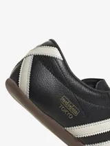 Zapatillas Adidas Tokyo negras con detalles en blanco y suela marrón.