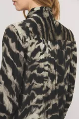 Camisa de viscosa con estampado animal print tipo zebra en tonos negros y grises, con diseño de cuello con lazo integrado, alforzas frontales con volados y mangas largas.