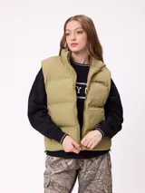 Chaleco puffer de la marca Rusty, color verde oliva, con cierre frontal y cuello alto. Presenta un diseño acolchado con costuras horizontales y logo de la marca estampado en el pecho.