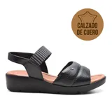 Sandalias de cuero negro con plataforma baja y tira trasera ajustable. La tira delantera es acolchada y tiene un detalle metálico. La tira del empeine es elástica con diseño geométrico en blanco y negro.