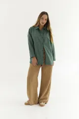 Camisa blanca de algodón con botones marrones, corte holgado y mangas largas.