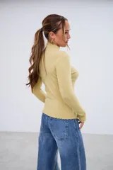 Polerita de manga larga color pistacho, con cuello alto y bordes ondulados en cuello, puños y dobladillo.