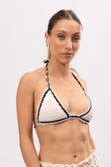 Top de bikini tejido a crochet color crudo, con terminaciones en negro y forro interior.