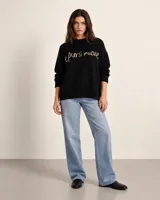 Sweater de punto negro oversize, con cuello redondo y hombros caídos, de manga larga y silueta amplia. Presenta bordado artesanal en el frente con la frase "e pur si muove" y líneas en contraste en los hombros.