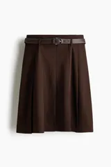 Pollera a la rodilla de tiro alto, de punto plisado color marrón, con elástico oculto en la cintura y cinturón incorporado de tejido revestido con hebilla metálica.