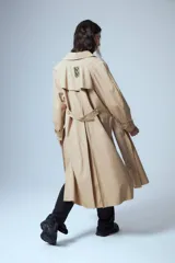 Trench midi color camel confeccionado en algodón y nylon repelente al agua, con cuello clásico, cierre frontal con un botón, bolsillos laterales y tajos laterales. Tiene etiqueta RENÉE en la espalda.