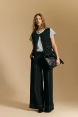 Pantalón largo color crema, tiro alto, de corte recto y ancho. Presenta costuras visibles en contraste y bolsillos delanteros.