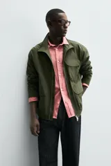 Parka de hombre color verde militar, corte regular, confeccionada en tejido técnico ligero. Presenta cuello subido, manga larga con puño ajustable y cuatro bolsillos frontales de plastrón con solapa. Cierre frontal con cremallera.