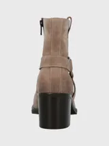 Bota corta de descarne color beige, con taco cuadrado y punta cuadrada. Presenta una correa con argolla metálica decorativa alrededor del tobillo y cierre lateral.