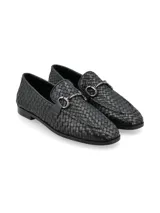 Mocasín de cuero negro con diseño entrelazado, detalle de herraje metálico en el empeine y suela plana de goma.
