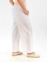 Pantalón ancho color blanco confeccionado en tela broderie con forro interior, de corte recto y tiro medio con cintura elástica.