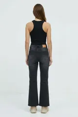Jean bootcut de tiro medio en color gris oscuro con efecto gastado, corte ajustado en la parte superior y ligeramente acampanado en la parte inferior, con terminación deshilachada en el bajo.