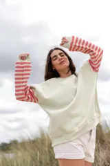 Buzo color verde claro con mangas largas a rayas horizontales rosas y blancas.