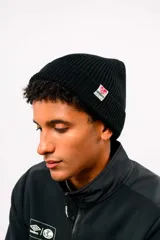 Gorro de lana tipo beanie de tejido acanalado, color blanco, con vuelta y pequeña etiqueta circular con el logo de Umbro en el lateral.