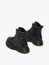 Borcego Dr. Martens Buzz 8 Eye Boot, color negro, confeccionado en cuero Milled Nappa. Presenta costuras blancas en contraste, cuello acolchado, cordones negros, suela robusta Buzz con ranurado DMs y las icónicas costuras amarillas en el ribete.