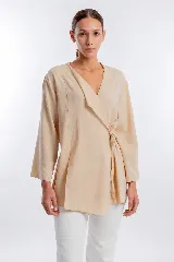 Blusa de manga larga color beige, de estilo cruzado con lazo lateral para atar y escote en V.