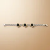 Pulsera de malla tejida en plata, con tres dijes circulares de ónix negro enmarcados en oro amarillo con detalles estriados.