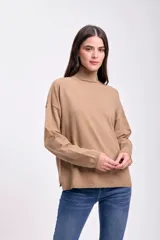 Polera de tejido de punto fino en color beige, con cuello alto, mangas largas y corte holgado.