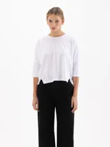 Remera de silueta relajada en tela de punto suave, con escote redondo, mangas 3/4 y tajos laterales que aportan movimiento.