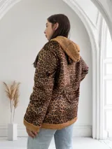Campera de corderoy con estampado animal print, forrada con piel sintética color beige. Tiene capucha, cierre con botones a presión y bolsillos laterales.