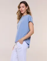 Remera de silueta amplia y relajada confeccionada en algodón y poliéster, de color verde, con escote a la base y mangas cortas de hombro caído. Presenta dobladillo enrollado y ruedo curvo.