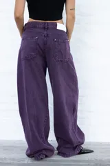 Jean de mujer color violeta oscuro, de corte holgado y tiro bajo. Presenta un efecto lavado y bolsillos traseros con costuras decorativas.