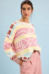 Buzo oversize de punto color marfil con diseño geométrico jacquard en tonos rosado, amarillo, celeste y marrón. Cuenta con cuello redondo y mangas largas.