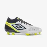 Championes de fútbol Umbro modelo Adamant, color blanco con detalles en negro, azul y amarillo neón. Presentan un diseño de media caña con cordones y tapones amarillos neón en la suela.
