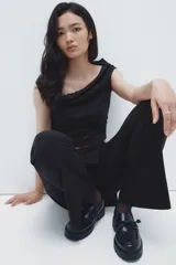 Pantalón acampanado de tiro alto con pollera mini superpuesta integrada, cierre frontal y botón.