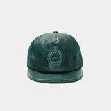 Gorra verde oscura tipo trucker con frente de cuerina, visera plana y paneles traseros de malla. Cuenta con escudo bordado en la parte frontal y cierre snapback ajustable.