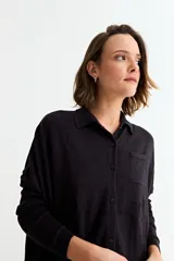 Cardigan negro de manga larga, con cuello camisero, botones frontales y un bolsillo en el pecho.