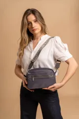 Bandolera de diseño moderno y funcional, confeccionada en nylon color marrón claro. Cuenta con múltiples compartimentos con cierre metálico, herrajes plateados y una correa ancha ajustable con detalle de marca.