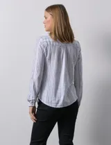 Blusa de lino estampada a rayas verticales en tonos blanco, verde, violeta, amarillo y rosa. Cuello a la base con escote en V y abertura central con botones. Delantera con bolsillos de parche. Mangas largas regulables con presilla y botón.