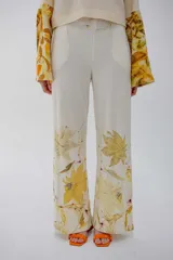 Pantalón de pierna ancha color crema con estampado de hojas amarillas.