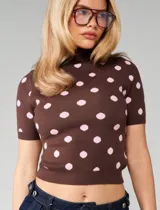Sweater de punto color chocolate con estampado de lunares rosados, cuello alto y mangas cortas. Presenta un calce ajustado al cuerpo con terminaciones acanaladas en cuello, mangas y ruedo.
