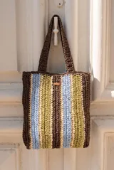 Bolso tipo shopper tejido de papel con diseño de rayas verticales en tonos marrón, celeste, verde oliva y beige. Cuenta con doble asa de hombro y detalle de etiqueta de marca en el frente.