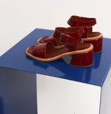 Sandalias de cuero color cereza, con tira ancha sobre los dedos, tira con hebilla al tobillo y taco cuadrado de madera.