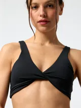 Top deportivo negro con detalle de nudo en el centro del busto y tirantes anchos. Confeccionado en poliéster con spandex.