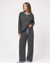 Pijama set de dos piezas compuesto por una remera de manga larga a rayas horizontales con cuello redondo celeste, y un pantalón largo de corte holgado a rayas verticales con cordón de ajuste en la cintura.