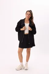 Conjunto deportivo compuesto por un buzo con cierre frontal y una falda corta, confeccionados en algodón liviano. El buzo presenta cuello alto, mangas largas con puños elásticos y un diseño holgado.