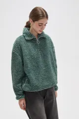 Buzo de textura afelpada con diseño de rayas horizontales finas en tonos marrones. Presenta cuello alto con cierre frontal parcial y mangas largas holgadas.