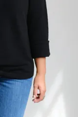 Sweter de punto color negro, con escote a la base y mangas largas con puños doblados. Presenta un corte holgado y diseño minimalista.